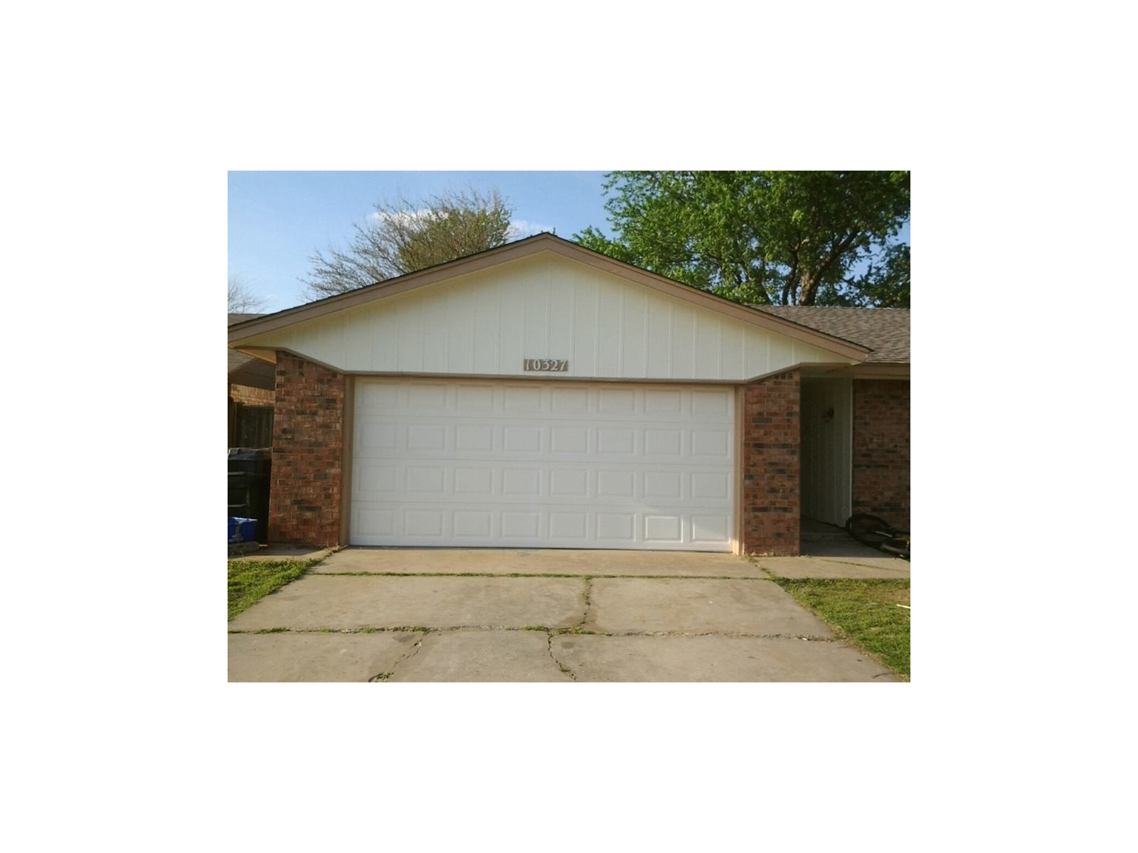 Light-blue two-story home with white trim, a garage and a neatly kept hedge.