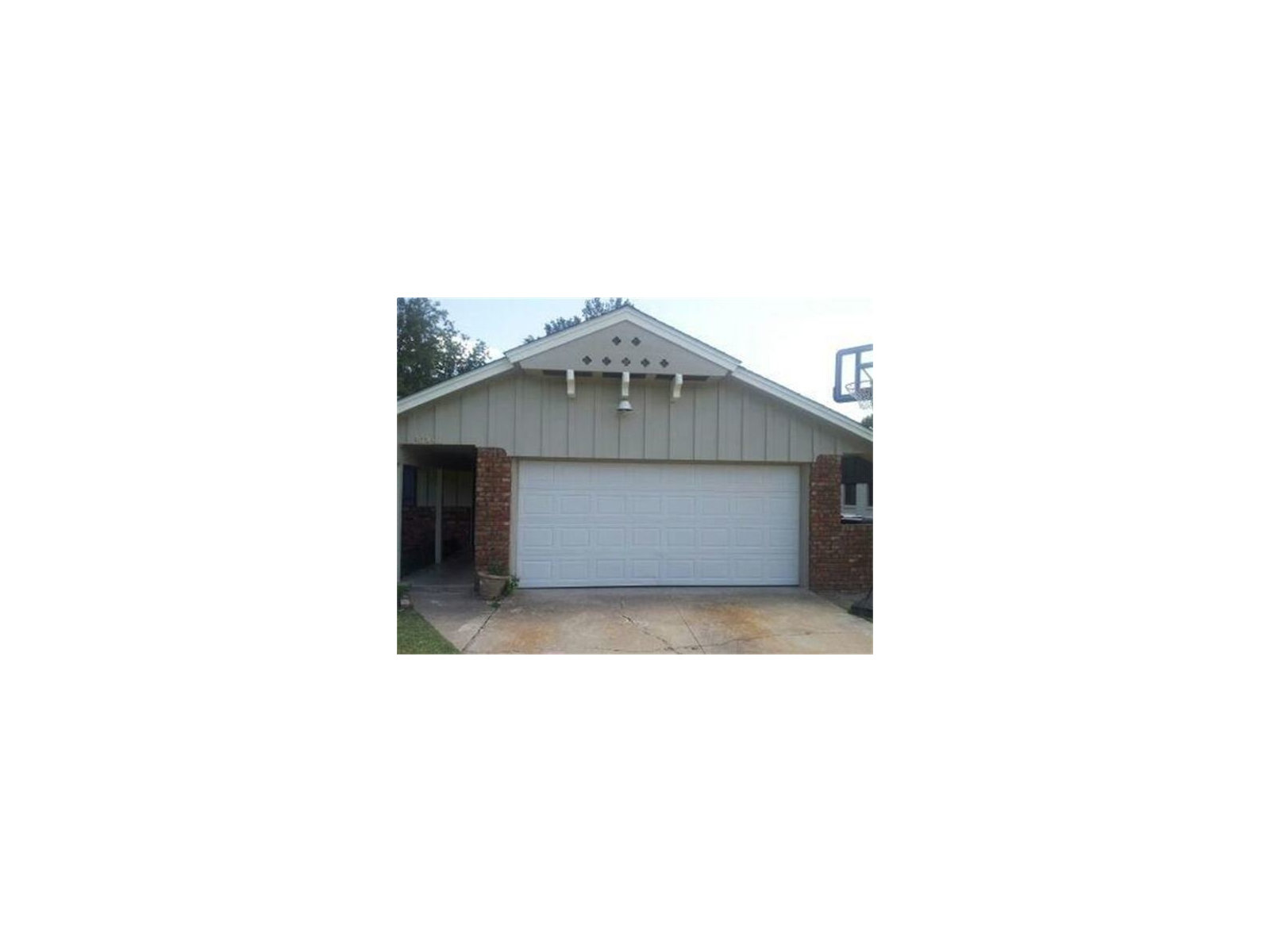 White double garage door below a cream gable on a brick home.
