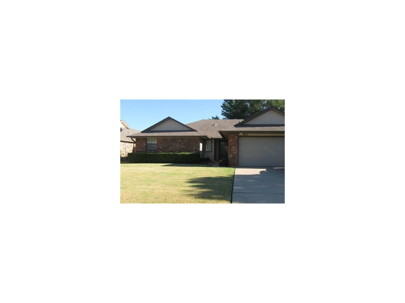 White garage door below a gable with decorative vents and brick side walls.
