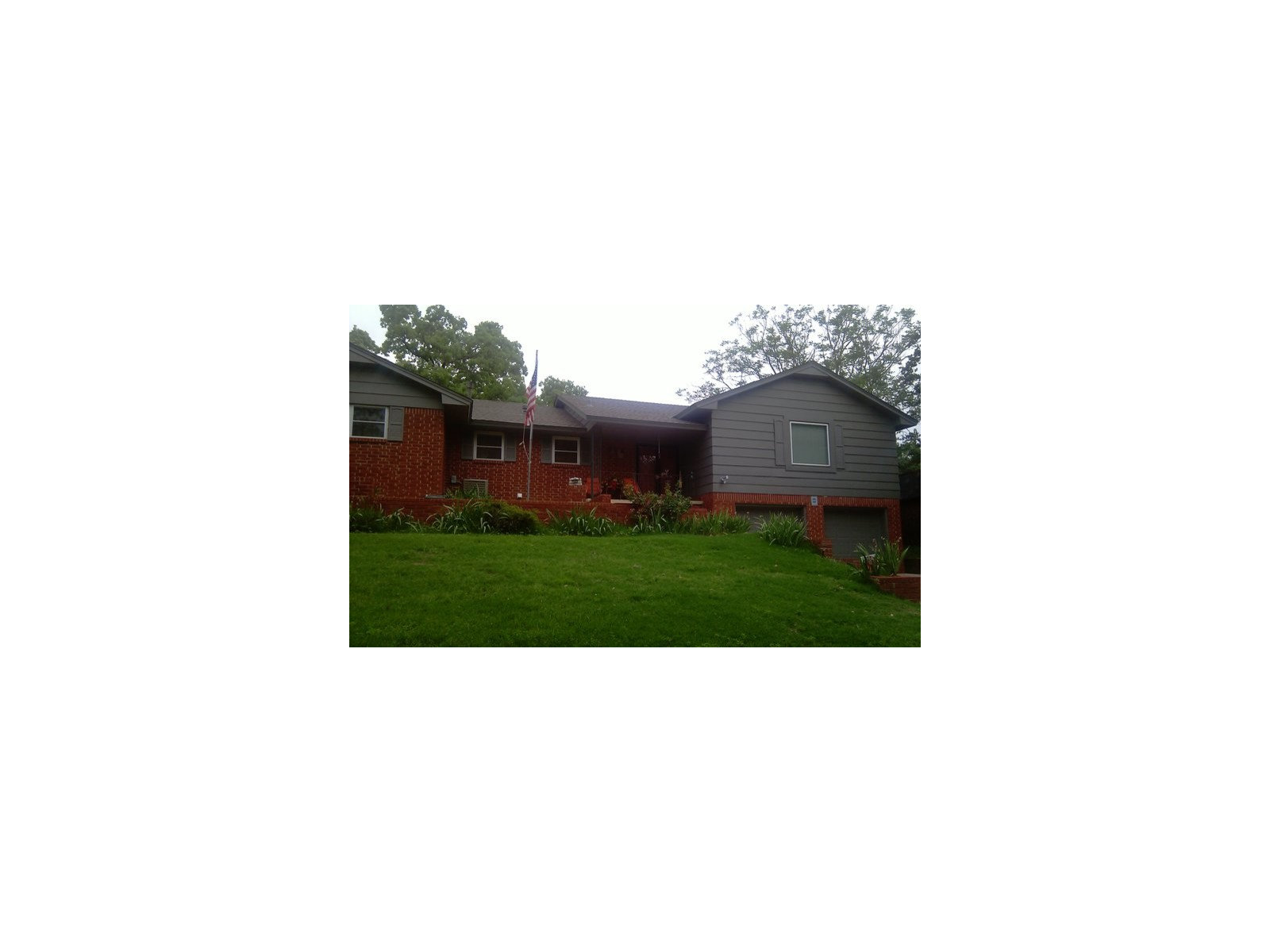 Light-blue two-story home viewed from the front corner with white trim and hedges.