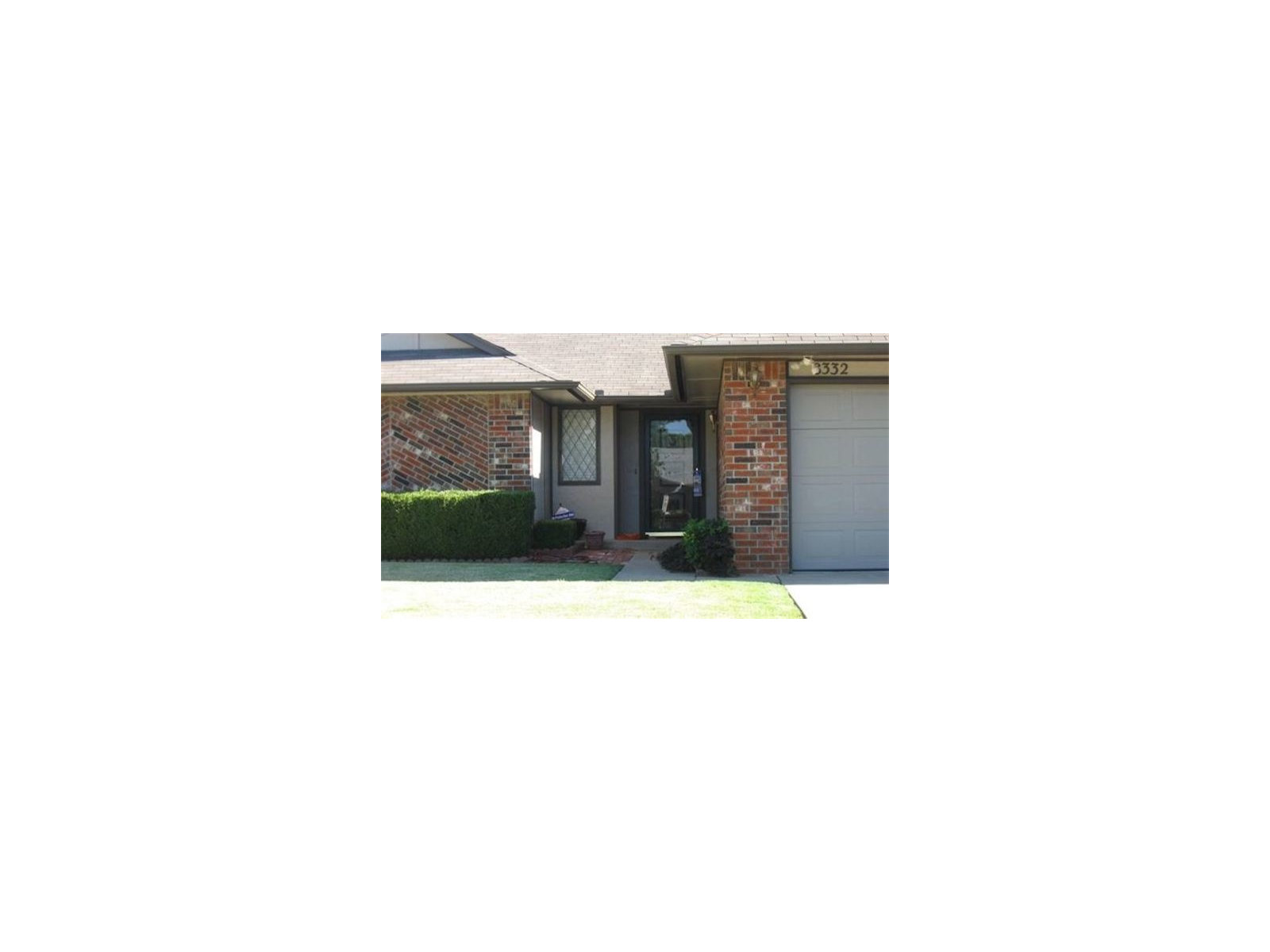 Dark gray gable above a white paneled garage door beside a brick wall.